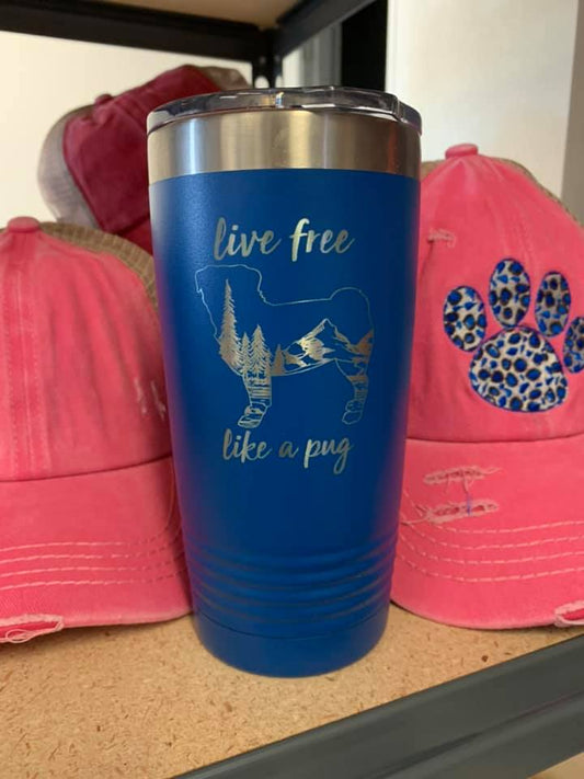 Image of an insulated tumbler in Royal with metal rim, clear plastic lid, and a pug silhouette filled with a mountainous scenery and the words "live free like a pug" laser etched in the side of the cup.